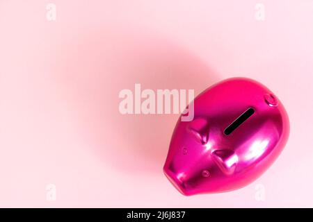 Bright pink piggy bank for coins on light rose background with copy space top view. Stock Photo