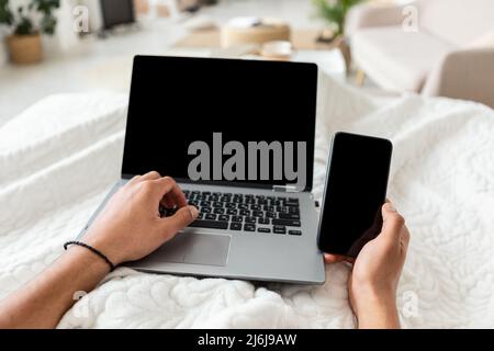 Man Using Laptop And Smartphone With Blank Screen Indoor, POV Stock Photo