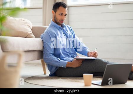 Portrait of Arab man using laptop and writing Stock Photo