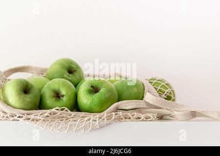 Green apples in a string bag on a white background. Stock Photo