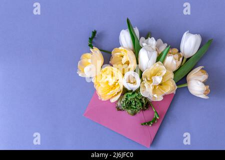 Flowers in an envelope on a colored background, flat lay. Stock Photo