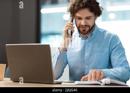 Business man talking on phone at office, reading diary Stock Photo