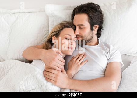 Top view of young affectionate couple sleeping in bed, embracing each other. Loving relationships and marriages Stock Photo