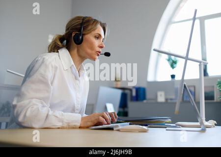 Business woman helpline operator in headset working at computer Stock Photo