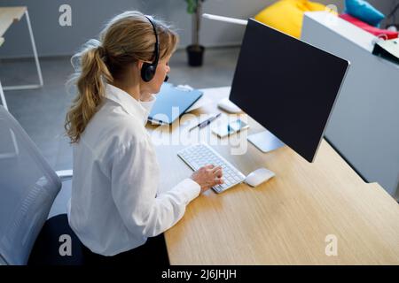 Pretty female call center operator working on computer in office Stock Photo
