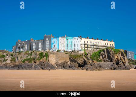 Tenby South Beach, view in summer of people walking beneath colourful property sited on cliffs overlooking South Beach in Tenby, Pembrokeshire, Wales Stock Photo