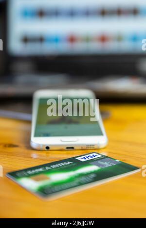 Belgrade, Serbia - April 15 2022 : VISA credit card on the table with smartphone and laptop in the background. Focus on VISA logo Stock Photo