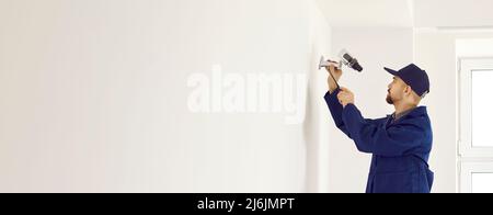 Copy space banner background with worker installing surveillance camera on white wall Stock Photo