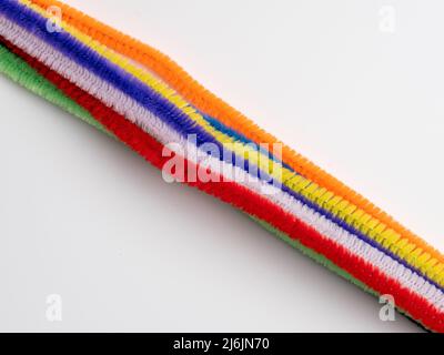 Diagonal pattern of colored neon pipe cleaners on a white background Stock Photo