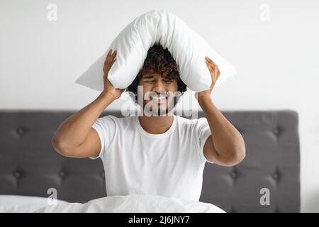 Sick indian guy suffering from headache, sitting in bed Stock Photo