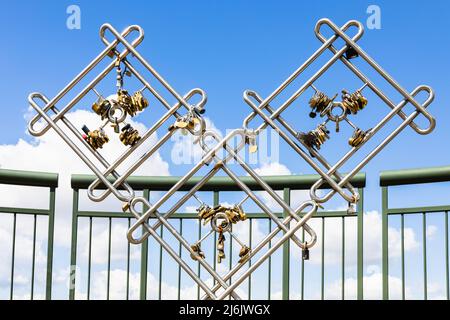 Closeup view of love padlocks hanging on a bridge fence Stock Photo
