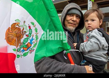 Detroit, Michigan USA - 1 May 2022 - A man and a small child watch the Cinco de Mayo parade in Detroit's Mexican-American neighborhood. Thousands lined the street for the annual parade, which returned in 2022 after a two-year hiatus due to the pandemic. Cinco de Mayo celebrates a Mexican victory over the French on May 5, 1862. Credit: Jim West/Alamy Live News Stock Photo