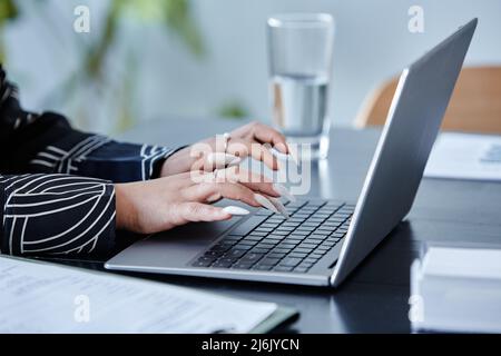 Close up of young black woman with long manicure typing at laptop keyboard while working in office, copy space Stock Photo