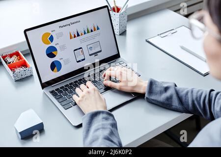 Close up of young professional doing marketing research while using laptop and looking at data charts on screen Stock Photo