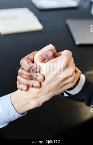 Close up of two business partners shaking hands in unity at meeting table, copy space Stock Photo