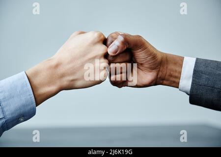 Close up of two business partners fistbumping in unity at meeting table, copy space Stock Photo