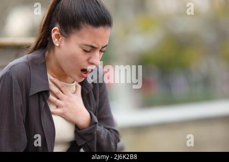 Stressed woman having problems to breath sititng in a park Stock Photo