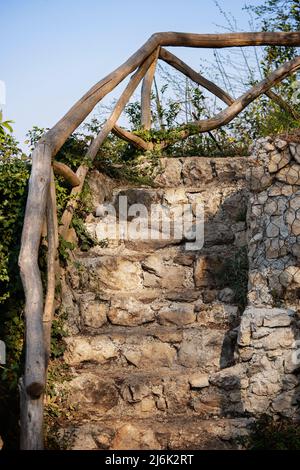 Old stone stairs overgrown by plants. Close up of ancient stone stairway. Stock Photo