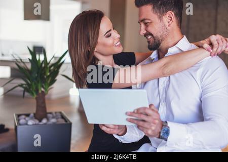 Happy young caucasian modern couple holding tablet indoors Stock Photo