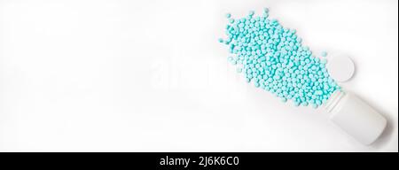 Banner. Blue pills are scattered from a white jar on a white background. Stock Photo