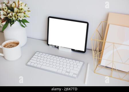 Stylish feminine workspace with graphic designer tablet mockup, keyboard, pen, cup of coffee, office stationery, vase of flowers. Stock Photo