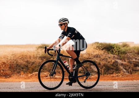 Side view of professional woman cyclist riding her bike outdoors Stock Photo