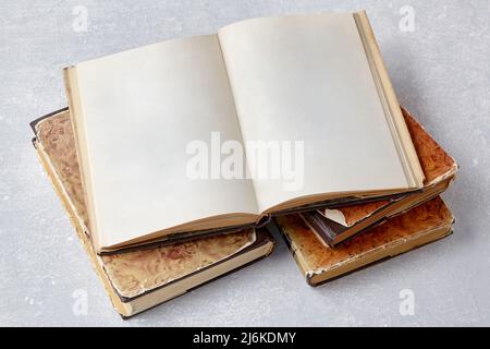 Open vintage book notepad with blank pages lies on a stack of old shabby books Stock Photo