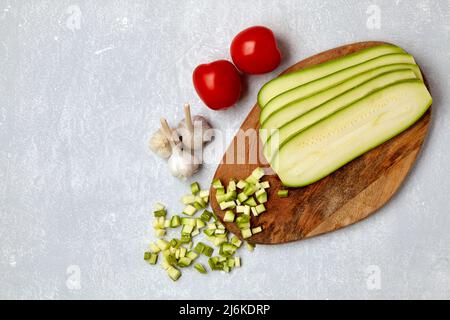 Sliced courgette vegetables on a wooden cutting board, tomatoes and garlic Stock Photo