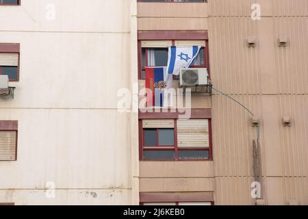 The national Israeli and Russian flag hangs outside the window of an Israeli apartment building. During Russian attacks in Ukraine. Russian - Ukraine Stock Photo