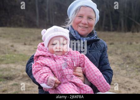 Grandmother walking with her granddaughter outside in the park at early spring. Stock Photo