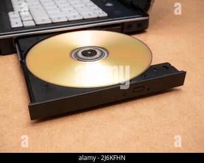 CD DVD optical disc media inserted in a laptop computer disc tray, closeup, nobody. Films, movies software data storage and sharing, piracy, installat Stock Photo