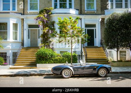 London - April 2022: An AC Cobra sports car parked outside attractive street of terraced houses Stock Photo