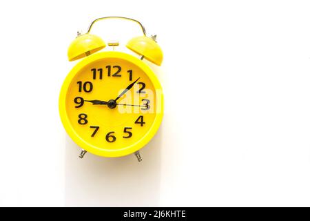 A yellow alarm clock lies on a white table, top view Stock Photo