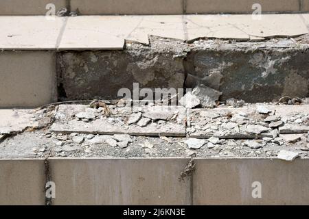 Steps with broken tiles on top. The tiles fell off the stairs. The old poor quality tile masonry at the entrance to the building. Repair work. Stock Photo