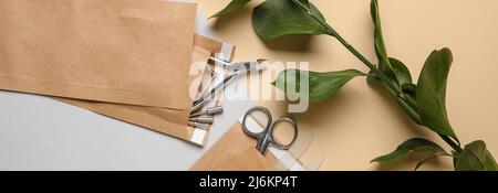 Paper bags with manicure instruments and green branch on color background Stock Photo