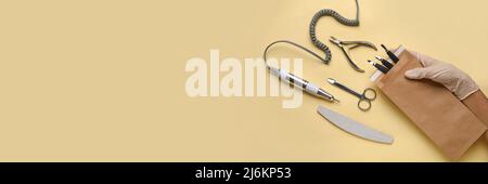 Female hand with manicure instruments on beige background with space for text Stock Photo