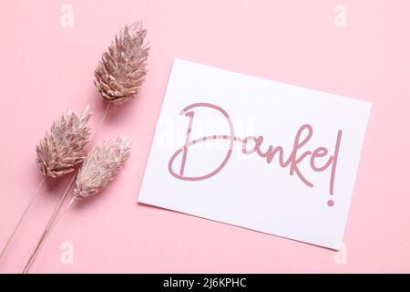 Card with word DANKE (German for Thanks) and floral decor on pink background Stock Photo