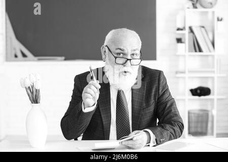 Teacher preparing for university exams. Professor holding a book and pointing. Teacher in college on university lecture. Stock Photo