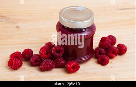 Sweet raspberry jam in jar and berries on wooden surface, nobody Stock Photo