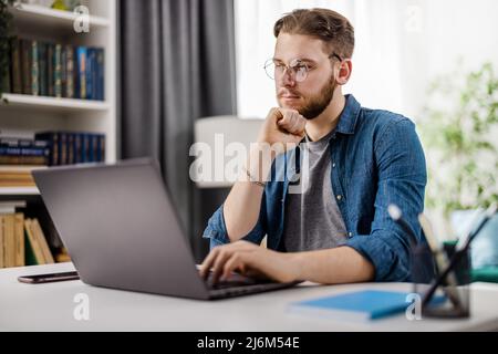 Thoughtful man with laptop at home Stock Photo