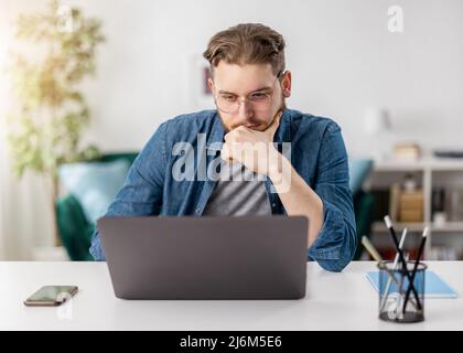 Pensive man with laptop at home Stock Photo