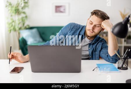 Tired freelancer working on laptop Stock Photo