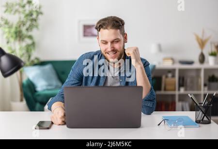 Man reading good news on laptop Stock Photo