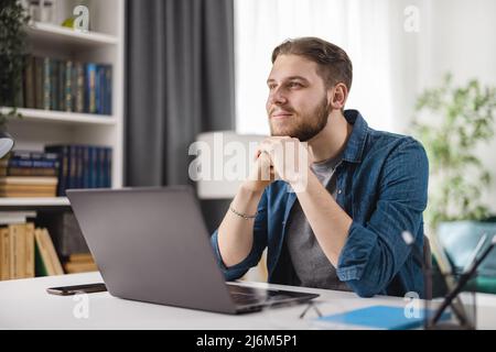 Dreamy man with laptop at home Stock Photo