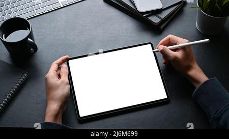 Overhead image, A man using stylus pen and working on digital tablet at his modern black workspace. Stock Photo