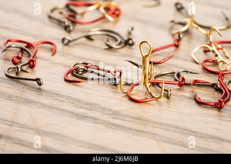 Small fishing hooks of different shapes, colors and sizes on a wooden table Stock Photo