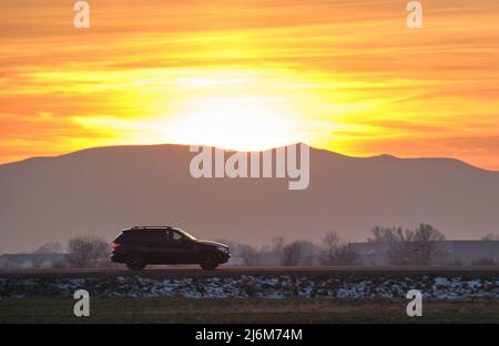 SUV car driving fast on intercity road at sunset. Highway traffic in evening Stock Photo