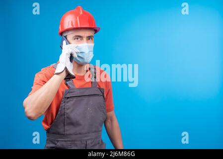 Man in builder uniform talking on smartphone during epidemic Stock Photo