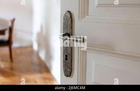 Door open close up view. Retro doorknob on white vintage wooden door, blur floor parquet, classy office interior Stock Photo