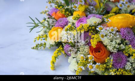 Fresh colorful wild flowers and herbs on a marble table, close up. Spring, garden nature. Women or Mothers day celebration, flower wreath bouquet deco Stock Photo